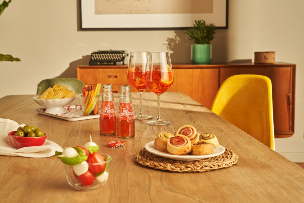 A beautifully arranged table featuring Sanbittèr and vibrant appetizers, perfect for commercials and campaigns showcasing elegance and inviting moments.