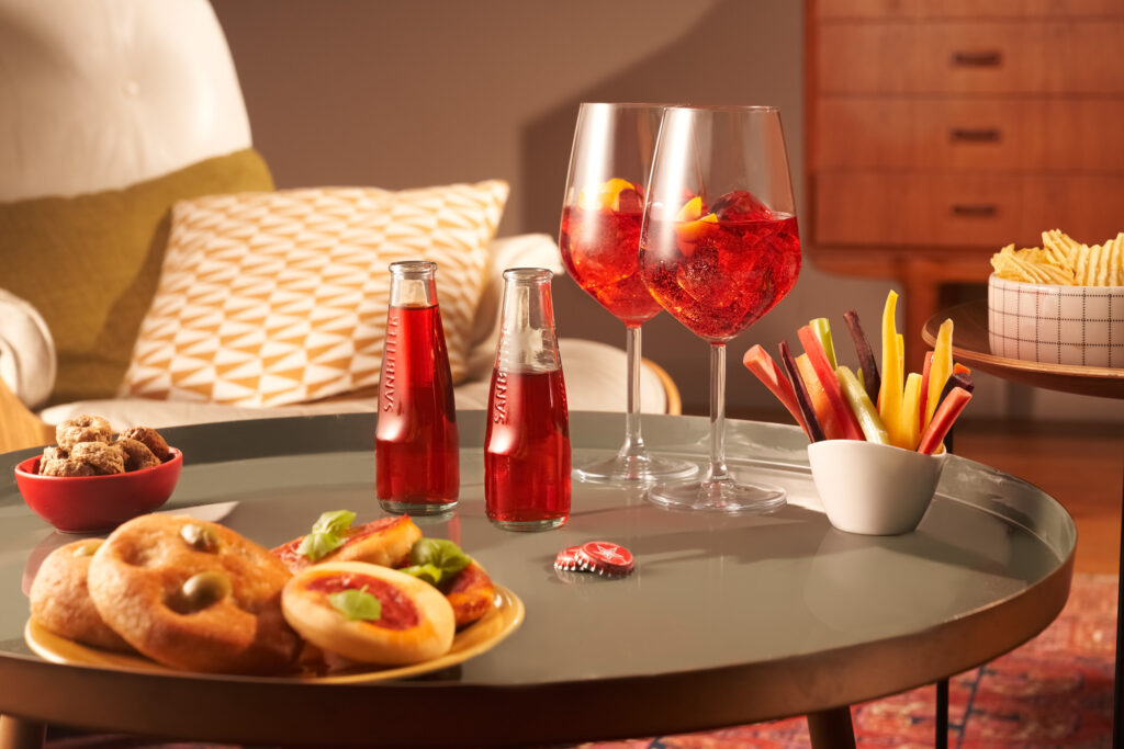 A warm and stylish setup of Sanbittèr drinks, paired with savory snacks and desserts. Capturing a cozy and relaxed ambiance for commercials and campaigns.