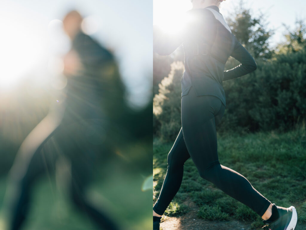 A trail runner adjusts her gear while standing under dappled sunlight in the countryside. The scene captures focus and readiness in a natural outdoor setting.